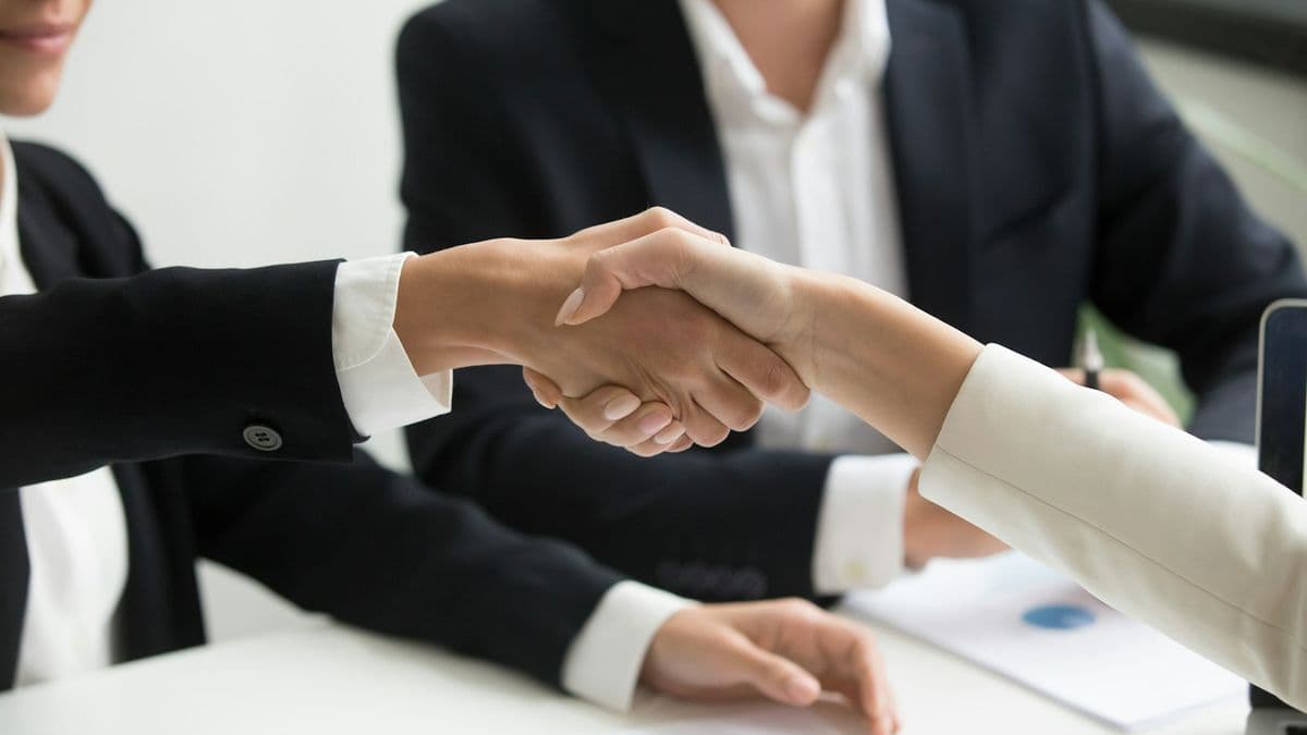 Pamela greeting a client with a handshake after a signing